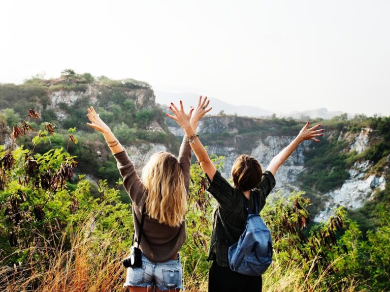 2 women holding hands up by canyon