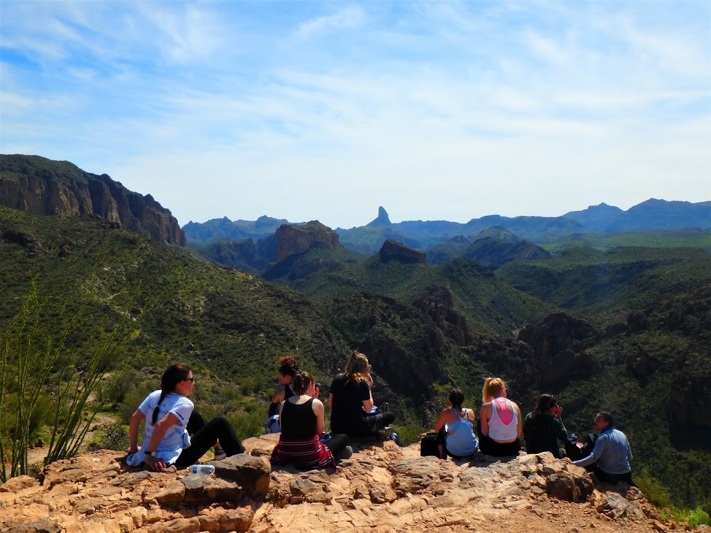 women sitting on mountainside looking at view