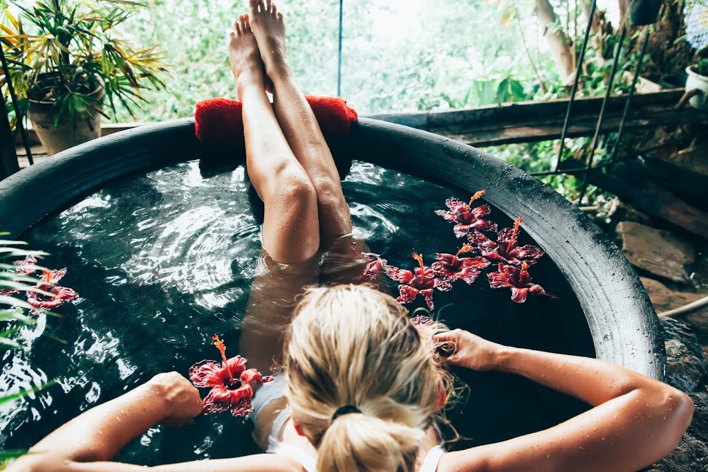 Woman relaxing in round outdoor bath with tropical flowers